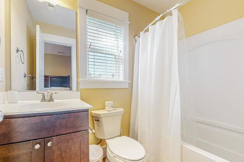 a bathroom with a toilet and a sink and a shower at Hola Beaches in Corolla