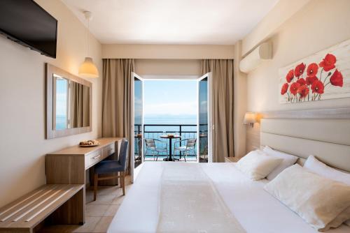 a hotel room with a bed and a desk with a view at Canvas by Mitsis Belvedere in Benitses