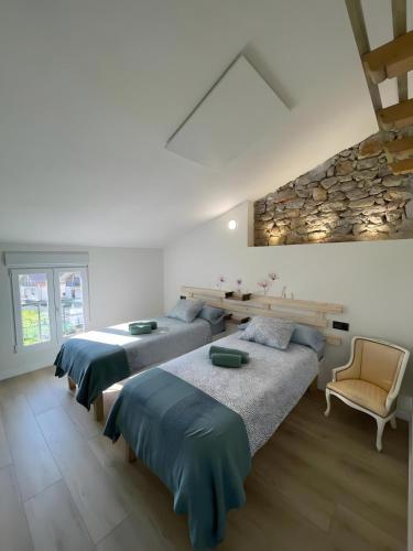 a bedroom with two beds and a stone wall at Verde & Mar in Castro-Urdiales