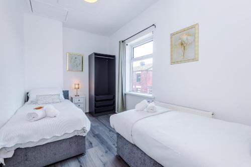 two beds in a room with a window at Stylish 2-Bed House Sleeps 4 in Saint Helens