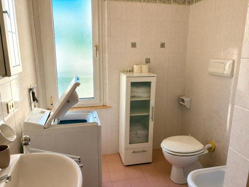 a bathroom with a toilet and a sink and a window at De Amicis Sea Home in Gabicce Mare