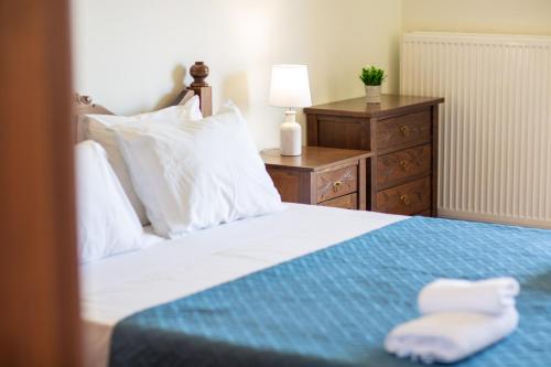 a bedroom with a bed with a blue blanket and a dresser at Kahlua Bay Apartments in Hersonissos