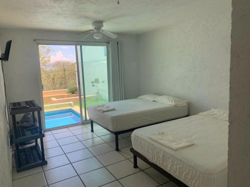 two beds in a room with a view of a pool at Casa Tikul in Temixco