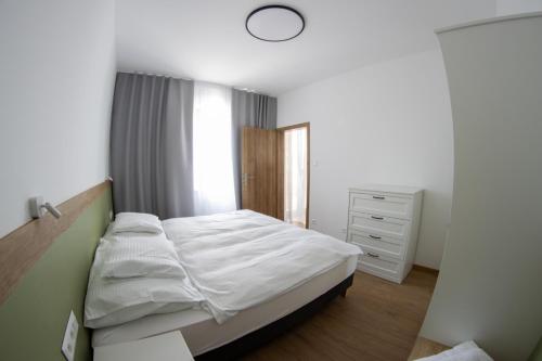 a small bedroom with a white bed and a window at Lebeco Apartman in Kolárovo