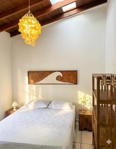 a bedroom with a white bed and a chandelier at Zeisa House in Maresias