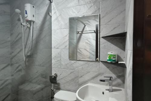 a bathroom with a sink and a shower with a mirror at Baan Thanakul Suvarnabhumi in Ban Khlong Nong Pru