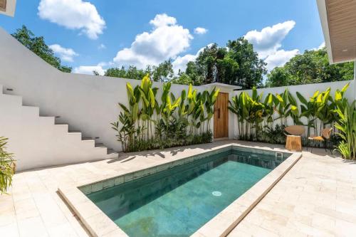 a swimming pool in the backyard of a house with plants at Villa Candi - Stylish Tropical Pool Villa in Ungasan