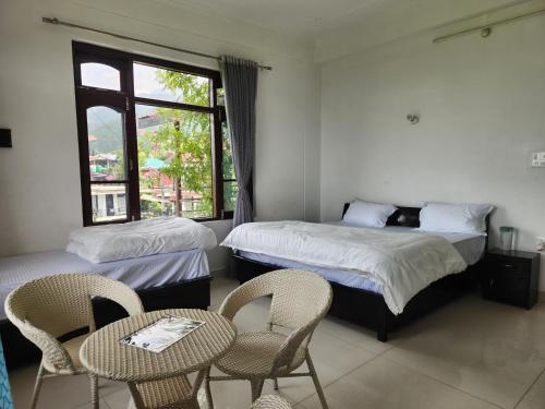 ein Zimmer mit zwei Betten, einem Tisch und Stühlen in der Unterkunft Draft Hotel Bir Billing At Landing Site in Bir