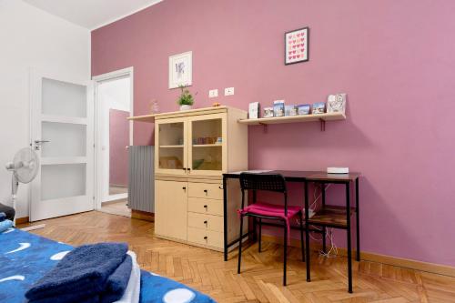 a bedroom with a desk and a pink wall at La Casetta di G&G in Varese