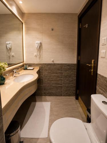 a bathroom with a sink and a toilet and a mirror at Zaha Al Madina Hotel in Medina