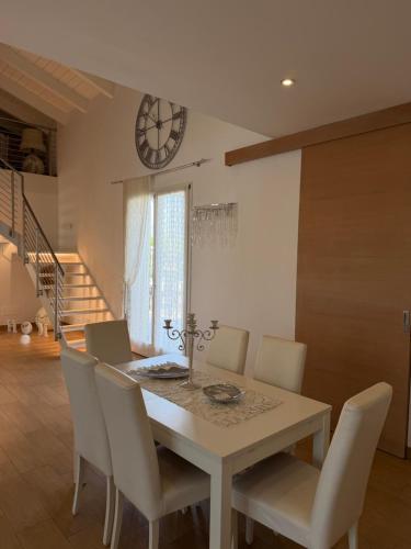 a dining room table with chairs and a clock on the wall at Villa Forni in Cesenatico