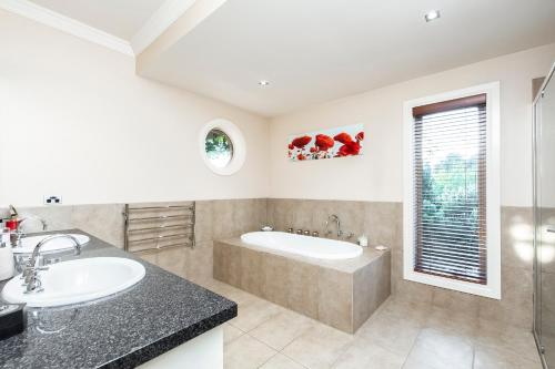 a bathroom with a tub and a sink at La Bella Vita in Batesford