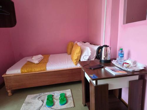a small bedroom with a bed and a desk with green slippers at EMJAYS guest house in Eldoret