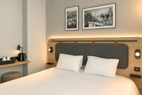 a bedroom with a bed with two white pillows at Campanile PRIME - Paris 15 Tour Eiffel in Paris