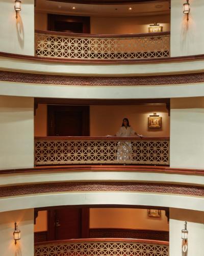a woman standing on a balcony in a building at Rosewood Jeddah in Jeddah