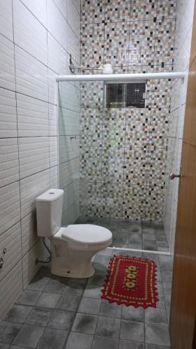 a bathroom with a toilet and a shower and a rug at Casa em Sítio, 7km da Cidade in Poconé