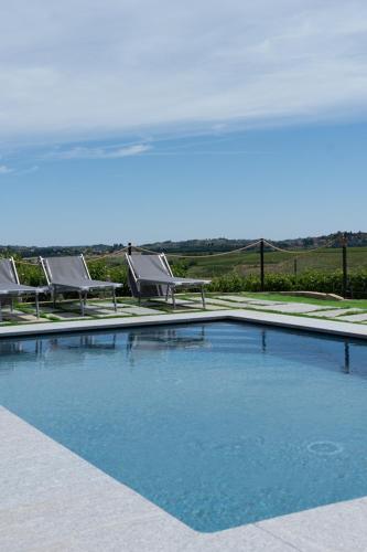 a large swimming pool with two lawn chairs at Da Elvira in Costigliole dʼAsti