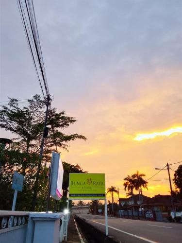 a sign on the side of a road at sunset at Bunga Raya Resort Parit Buntar in Parit Buntar