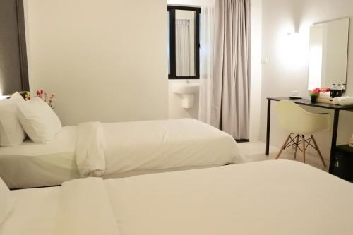 a hotel room with two beds and a mirror at Shane Hotel in Chiang Mai