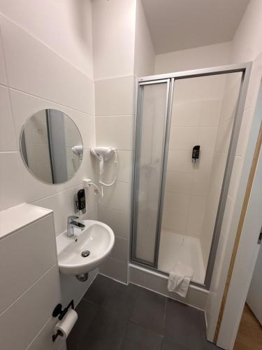 a white bathroom with a shower and a sink at Potsdamer Inn in Berlin