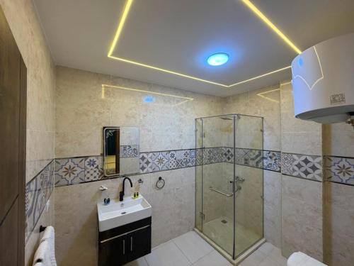 a bathroom with a glass shower and a sink at Royal Night Pyramids View Inn in Cairo