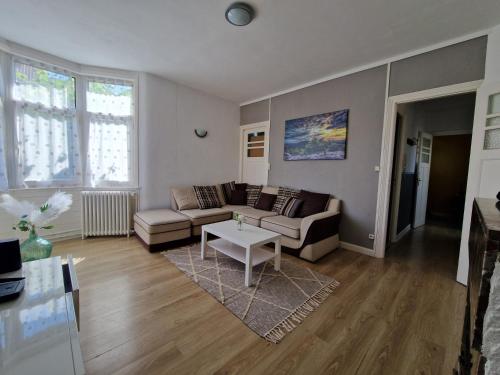 a living room with a couch and a table at Spacieux duplex familial proche Dunkerque et plage in Coudekerque-Branche