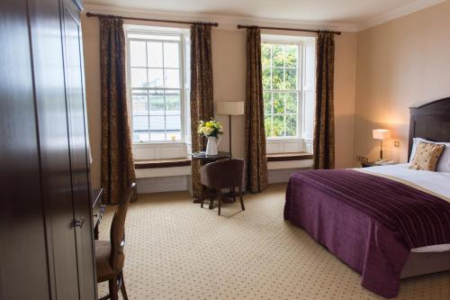 a hotel room with a bed and two windows at Baileys Hotel Cashel in Cashel