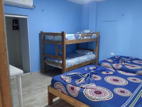 two beds in a room with blue walls at Villa faty in Coveñas