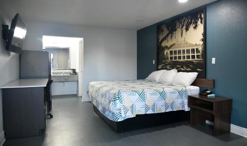 a bedroom with a bed and a painting on the wall at Studio 6 Suites Opelousas, LA in Opelousas