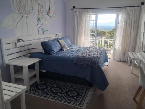 a bedroom with a blue bed and a window at Franmarel in Plettenberg Bay