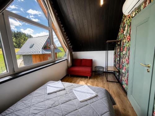 a bedroom with a bed and a window and a red chair at D'Pazur- sauna, jacuzzi in Białka Tatrzańska