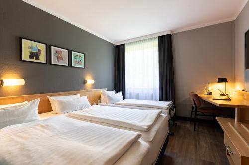 a hotel room with two beds and a desk at Garner Hotel Cottbus Süd by IHG in Cottbus