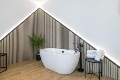a bathroom with a white bath tub in an attic at Apartamentos Surya Home Suites in Conil de la Frontera
