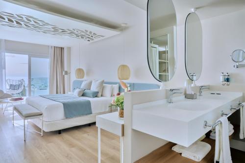 a bedroom with a bed and a sink and a mirror at Amare Beach Hotel Sancti Petri - Adults Recommended in Chiclana de la Frontera