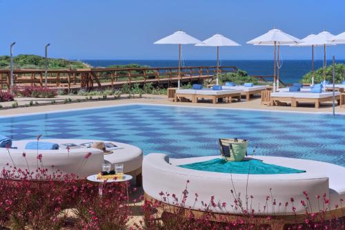 a pool with tables and umbrellas at a resort at Amare Beach Hotel Sancti Petri - Adults Recommended in Chiclana de la Frontera