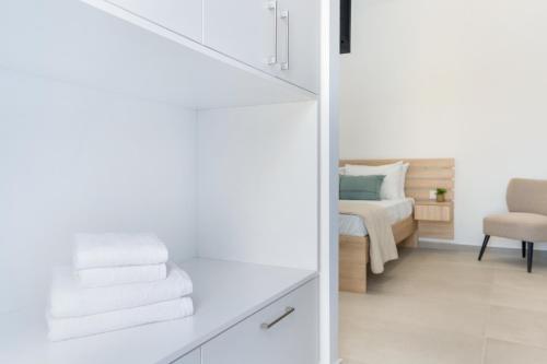 a white room with a bed and a chair at Khōra Suites Matala in Matala