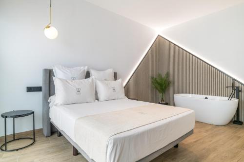 a bedroom with a white bed and a bath tub at Apartamentos Surya Home Suites in Conil de la Frontera