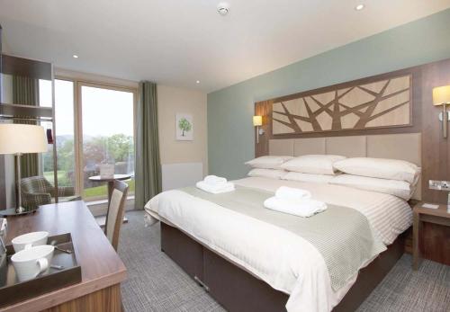 a bedroom with a large bed with white pillows at Drimsynie Estate Hotel in Lochgoilhead