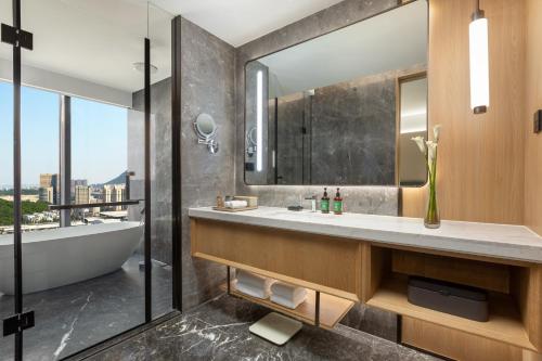 a bathroom with a tub and a sink and a mirror at Crowne Plaza Dalian Kerren in Dalian