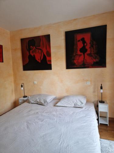 a bedroom with a white bed with three pictures on the wall at Chez raymonde in Teyran