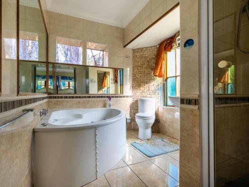 a bathroom with a tub and a toilet at Aurora Guest Units in Durbanville