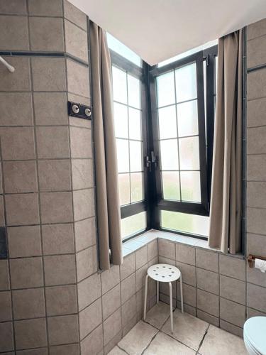 a bathroom with a stool and two windows at Apartamento playero Privado WiFi- MorroJable in Morro del Jable