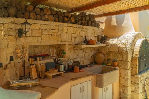 a kitchen with a sink and a stone wall at Villa Mirabello Tholos Adults Only in Kavoúsion