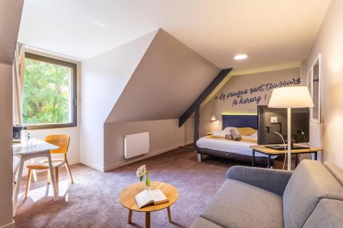 a living room with a bed and a couch at Hôtel Antares & Spa in Honfleur