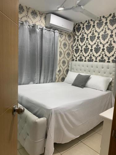 a white bed in a bedroom with a curtain at Casa Mamá Tere in Pantoja