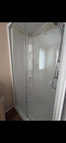a glass shower in a bathroom with at Dotties Den at Sunnysands in Llanddwywe