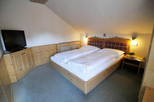 a bedroom with a large bed and a flat screen tv at Landgasthof Kirchenwirt in Grossraming