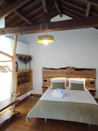 a bedroom with a large bed with a wooden headboard at Moinho da Quinta da Esperança in Ourém