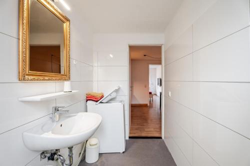 a white bathroom with a sink and a mirror at Haus Hauptstrasse 23a in Bühl