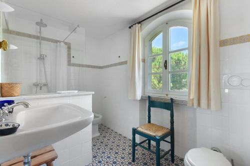 a bathroom with a sink and a toilet and a window at Villa Le Ginestre di mare in Capoliveri